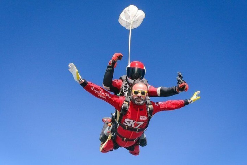 Two skydivers in red suits with parachutes. 4