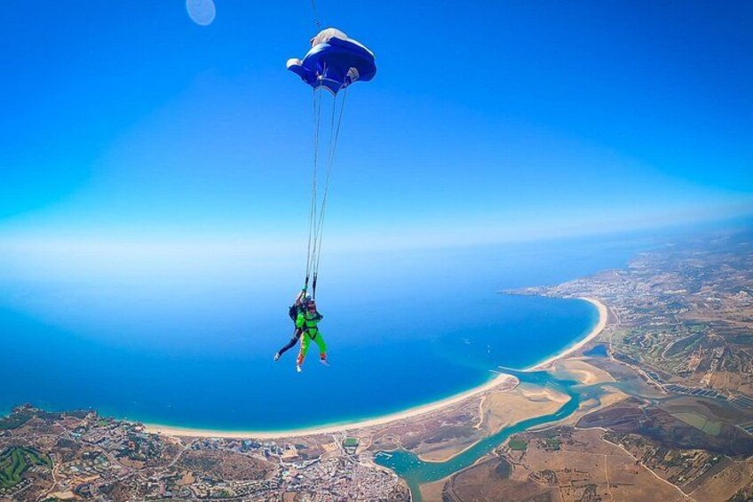 En person paraglider over et kystlandskab med frit udsyn til strand og vand. 4