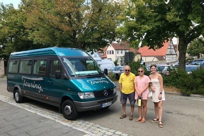 A green van with 'Touring' written on it, parked on a street with people standing beside it. 2