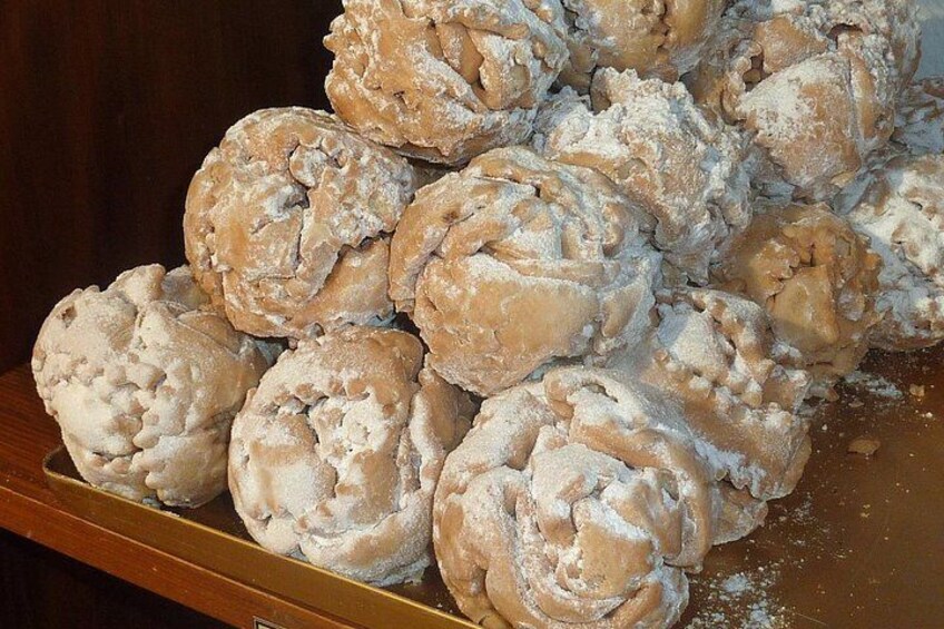 A pile of round, textured pastries dusted with powdered sugar. 4