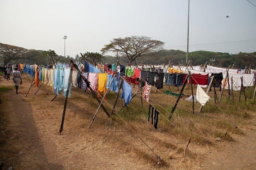 A rural area with clothes hanging on lines, a dirt path, and sparse vegetation. 3
