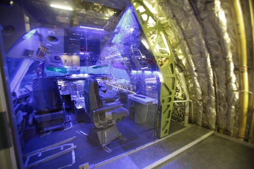 A spacecraft interior with control panels, seats, and metallic structures. 2