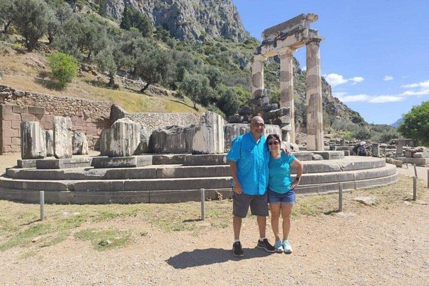 Ancient ruins with columns and stone structures, a person in a blue shirt, and another in a turquoise top. 5