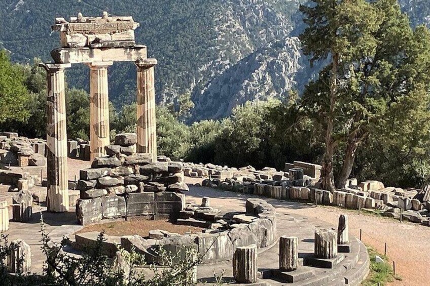 Ancient ruins with columns and stone structures, set against a mountainous backdrop. 3
