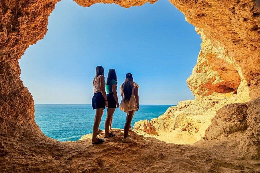 Two people standing in a natural rock formation with a view of the sea. 5