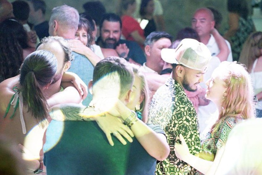 Un grupo de personas bailando en un espacio al aire libre lleno de gente. 5