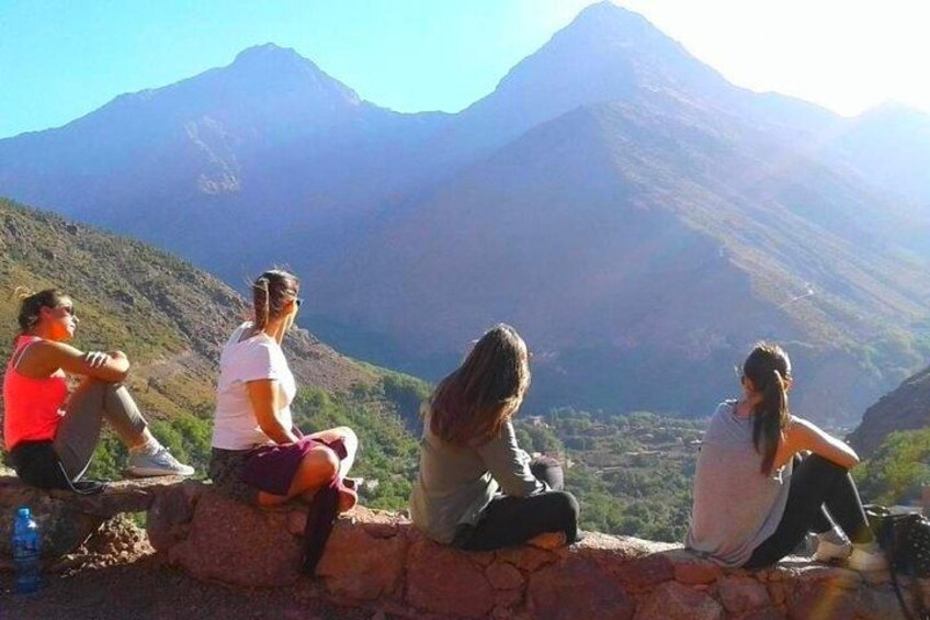 Cuatro personas sentadas sobre un muro de piedra con vistas a un paisaje montañoso. 2