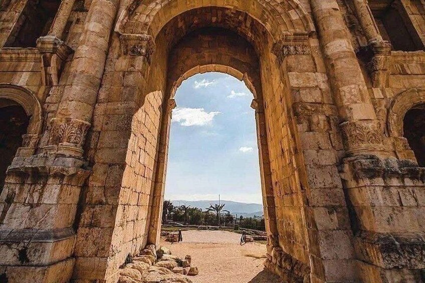 An ancient stone archway with intricate carvings, leading to a distant landscape with trees and mountains. 5