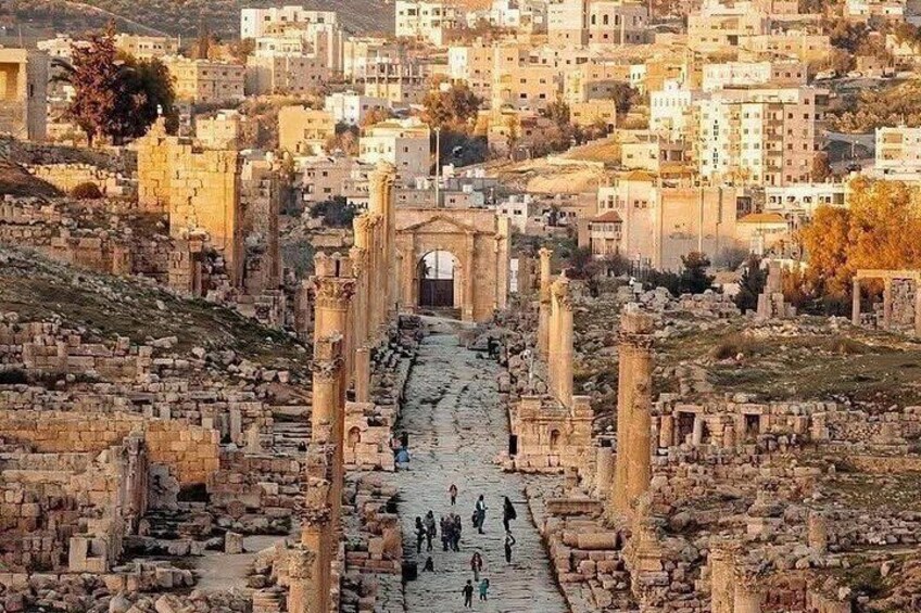 Ancient ruins with columns and a central archway, surrounded by modern buildings. 4