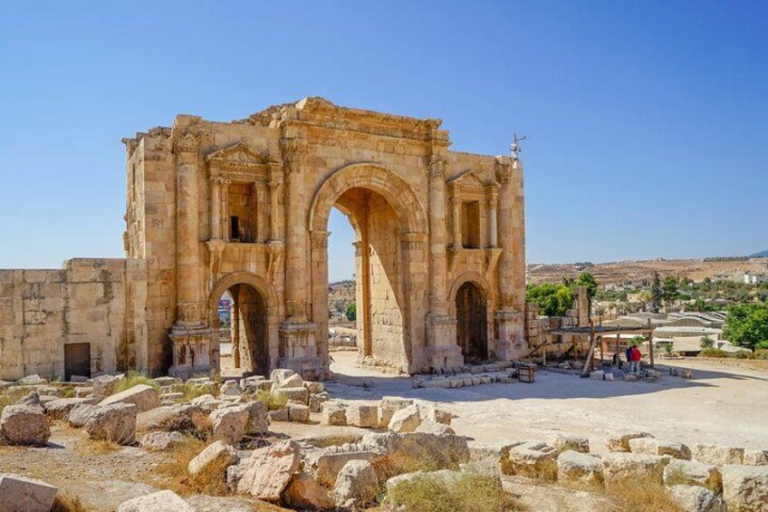 An ancient stone archway with columns, surrounded by ruins and rocks. 5