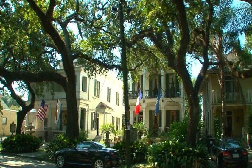 A street lined with historic buildings, American and French flags, and parked cars. 4