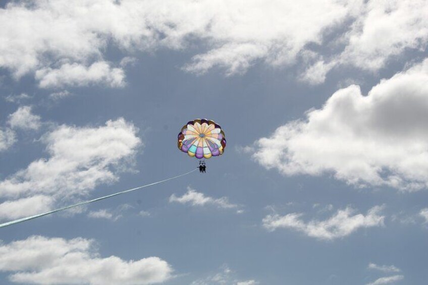 Una persona haciendo paracaidismo con un paracaídas colorido sobre un cielo nublado. 3