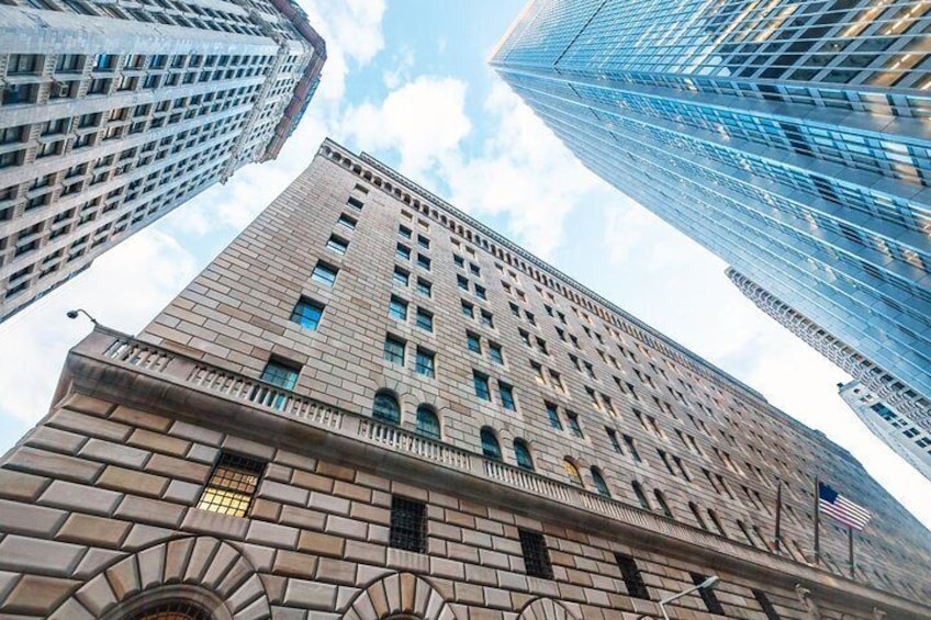 A tall building with a stone facade and multiple windows, surrounded by other high-rise buildings. 2