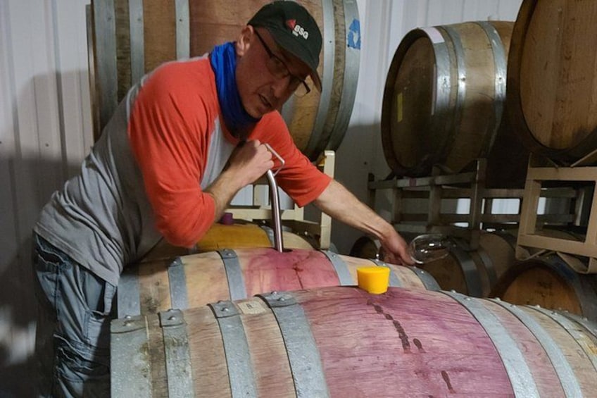 A person working with a large wooden barrel, using a tool to open it. 3