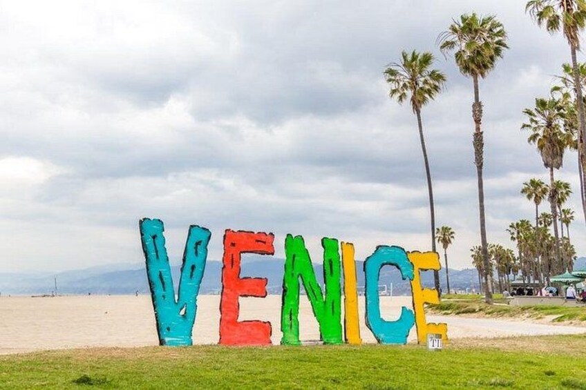 Colorful letters spelling 'VENICE' on a beach with palm trees in the background. 3