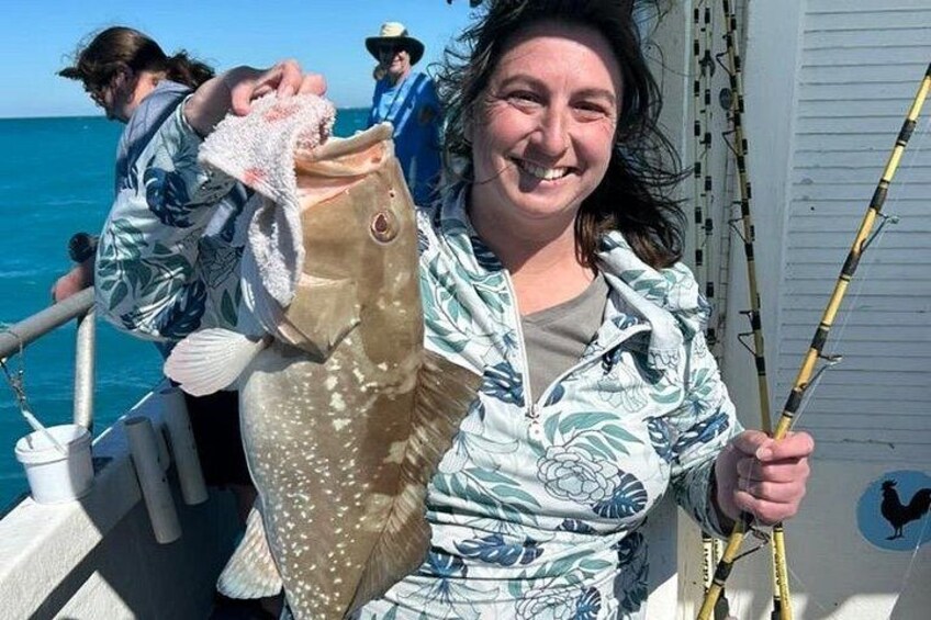 Eine Person hält einen Fisch und eine Angel auf einem Boot. 4