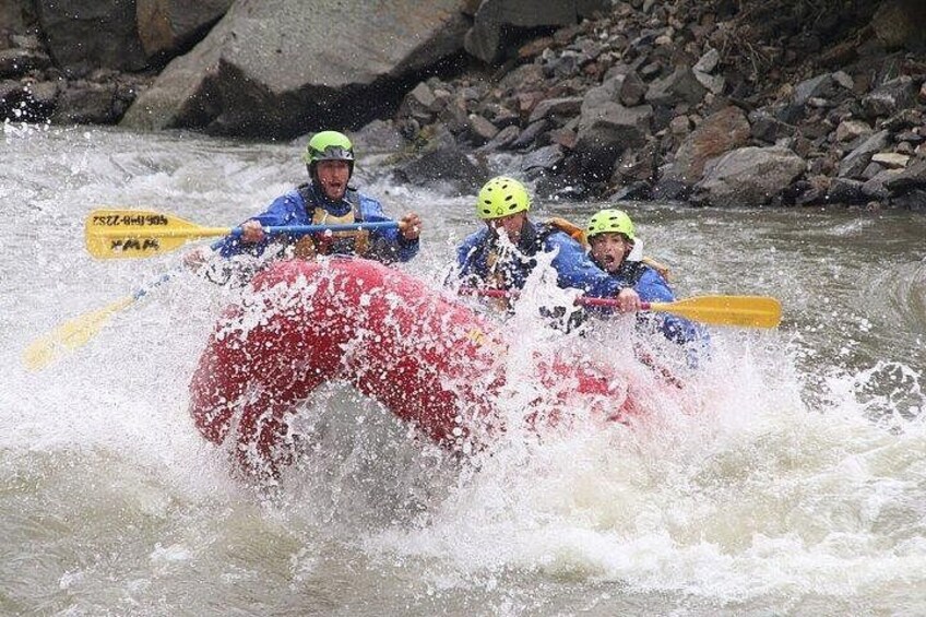 Three people in a red raft navigating a river. 3