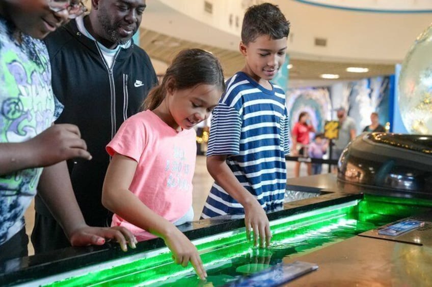Personer som spelar ett digitalt spel på en yta som lyser upp i grönt. 3