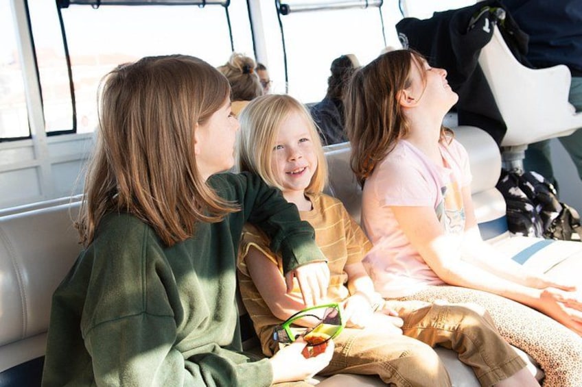 Three children sitting on a bench, one holding a snack. 3