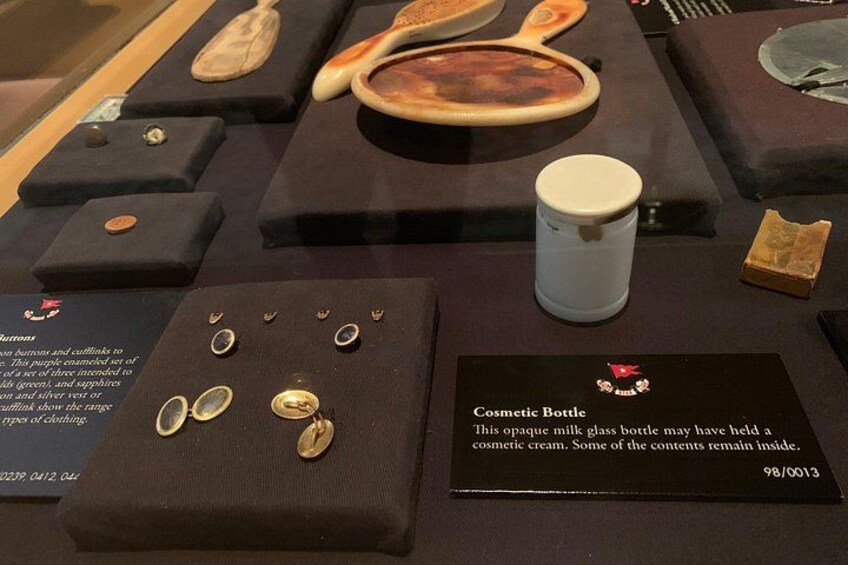 A display of historical artifacts including a cosmetic bottle, jewelry, and wooden objects. 2