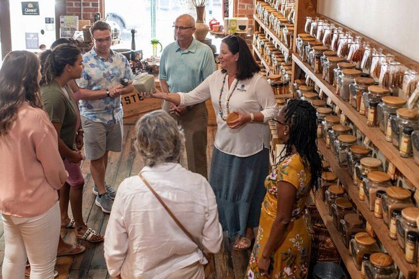 A group of people in a store with shelves of jars. 3