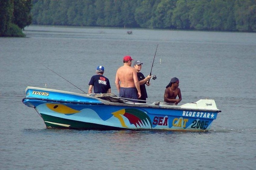 Un bote llamado 'SEA CAT 2005' en un lago, con tres personas pescando. 1