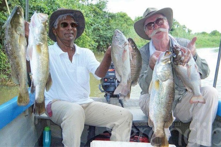 Dos personas en un bote sosteniendo peces. 2