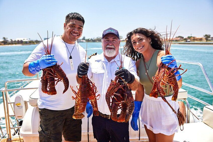 Three people on a boat holding lobsters. 1