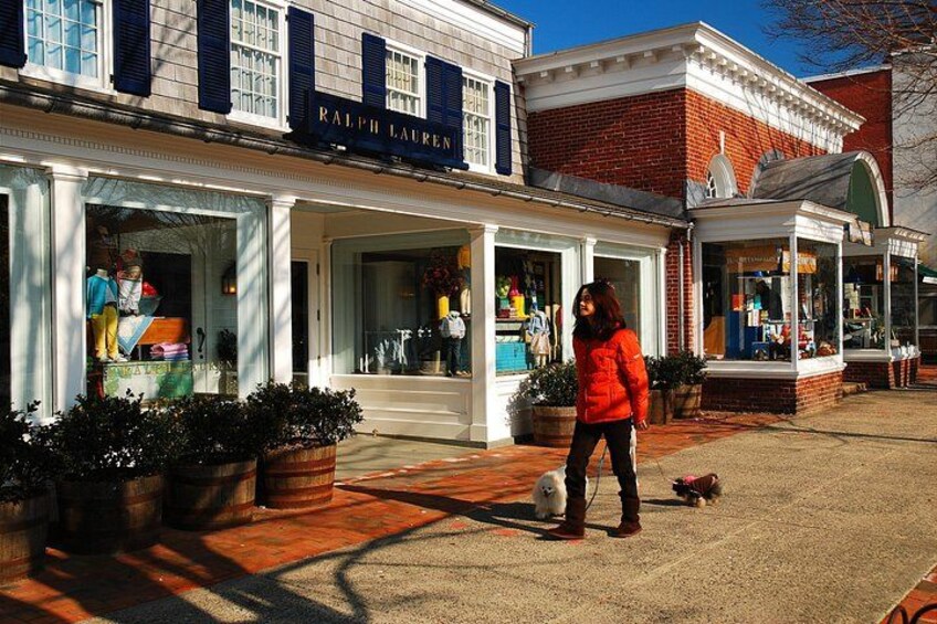 Una fachada con un letrero que dice 'RALPH LAUREN' y una persona con una chaqueta roja paseando un perro. 2