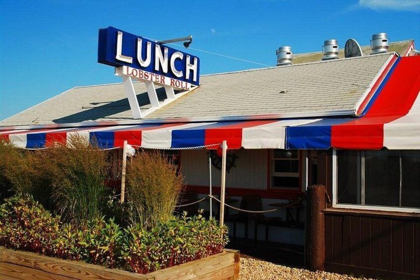 A restaurant with a sign that reads 'LUNCH LOBSTER ROLL' and a red, white, and blue awning. 2