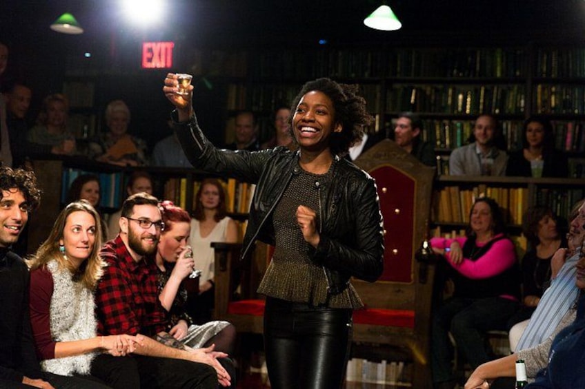 A person standing in front of an audience in a room with bookshelves. 5