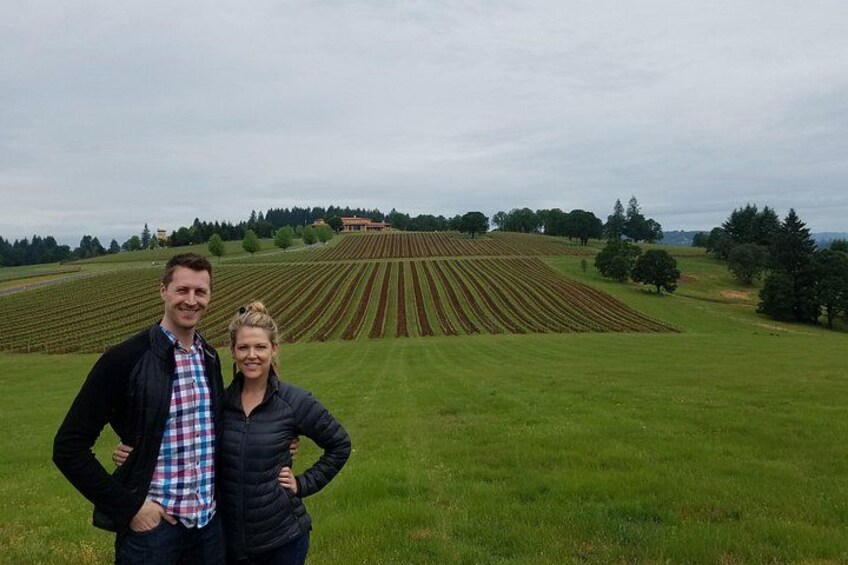 Un couple se tient debout dans un vignoble, au milieu de rangées de vignes. 3