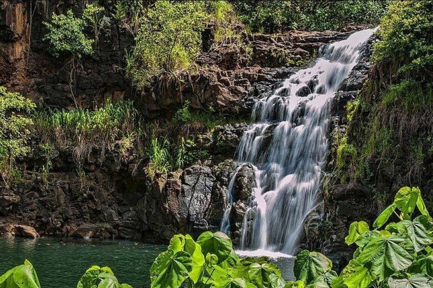 A waterfall cascading over rocky terrain with lush greenery at the base. 3