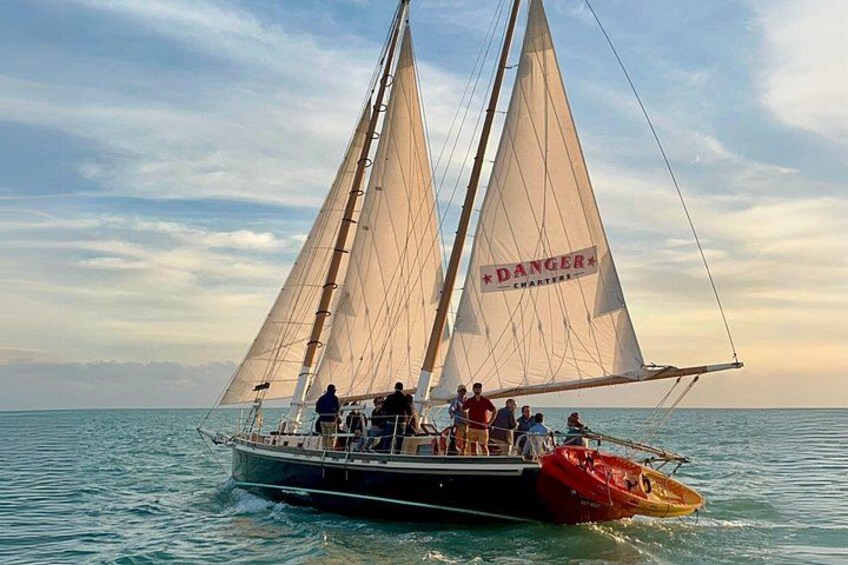 A sailboat with multiple sails on calm water. 3