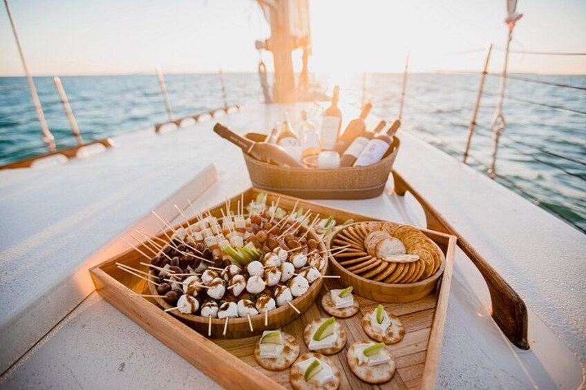 Un plateau en bois avec des brochettes de nourriture, un bol de pain et un panier de pain, le tout sur un bateau. 4