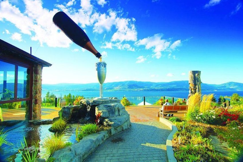 A stone pathway leading to a glass sculpture, surrounded by lush greenery and a scenic mountain view. 1