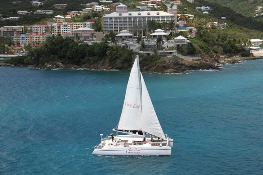 Un velero llamado 'The Coral' en un mar tranquilo, con un pueblo costero al fondo. 4
