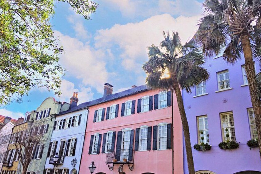 Una hilera de edificios coloridos con contraventanas, una palmera y un farol. 1