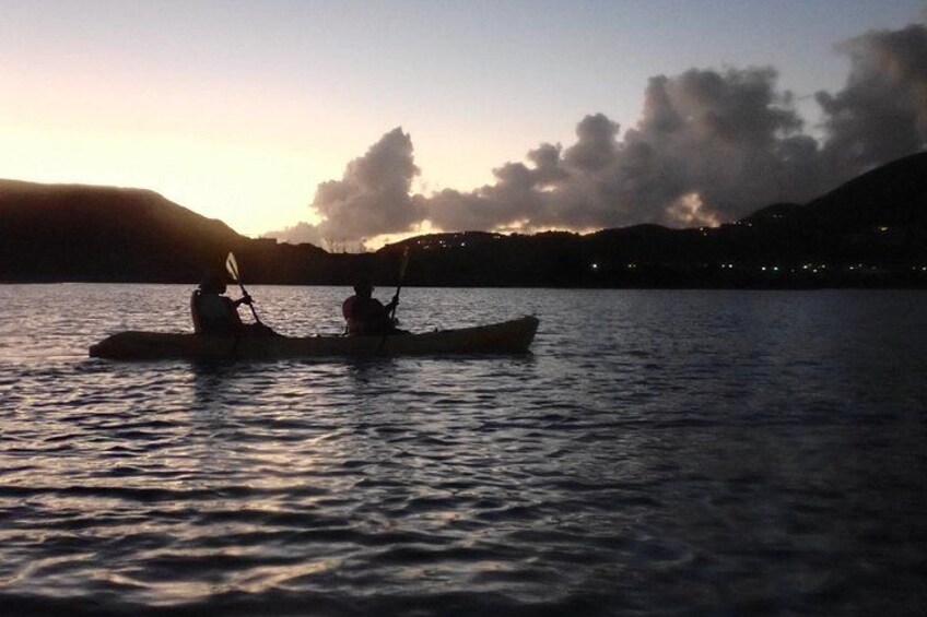 Two people kayaking on a calm body of water during sunset. 2