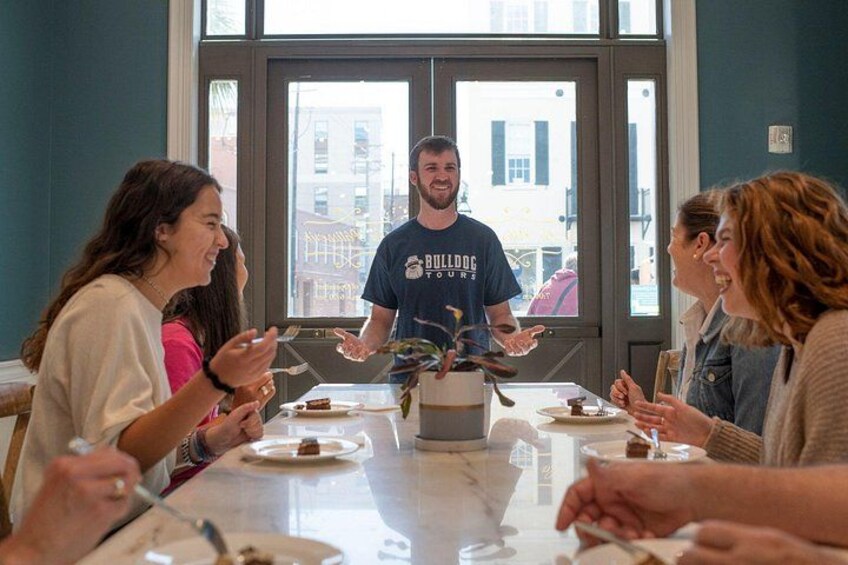 A group of people dining at a table with a waiter in a blue t-shirt. 2