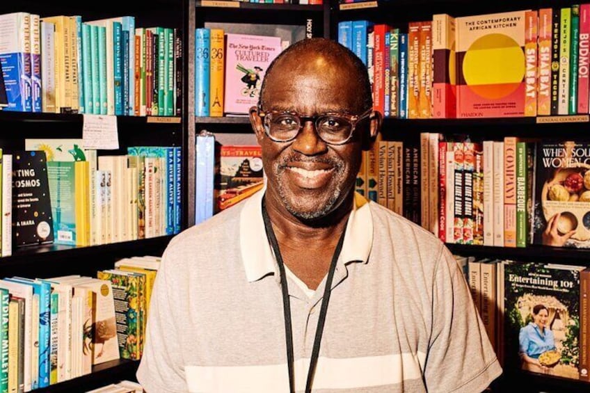 A person standing in front of a bookshelf filled with various books. 5