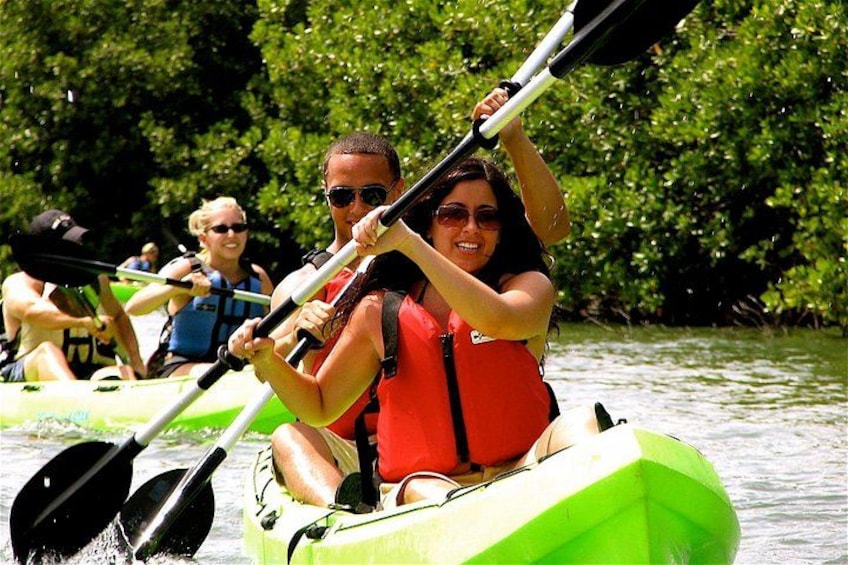 People kayaking on a river surrounded by greenery. 1