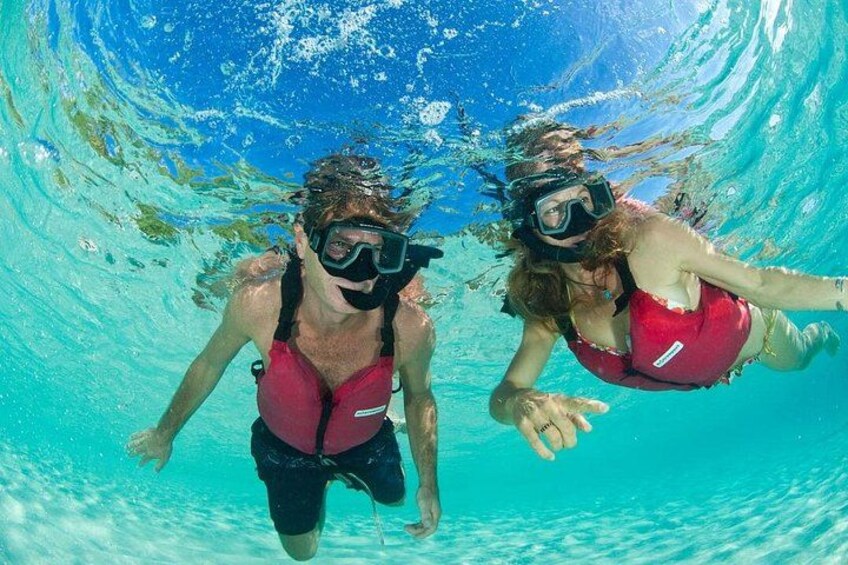 Dos personas haciendo snorkel bajo agua en aguas azules y transparentes. 2