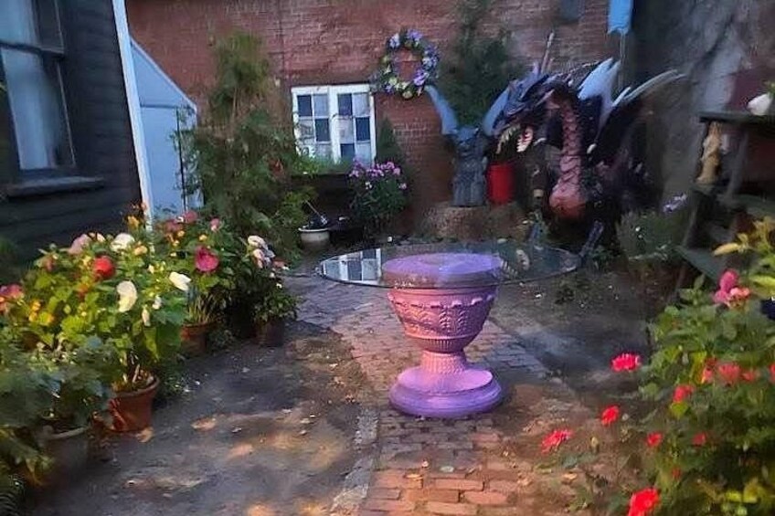 Un jardin agrémenté d’une urne violette, de plantes en pot et d’un chemin bordé de briques. 5