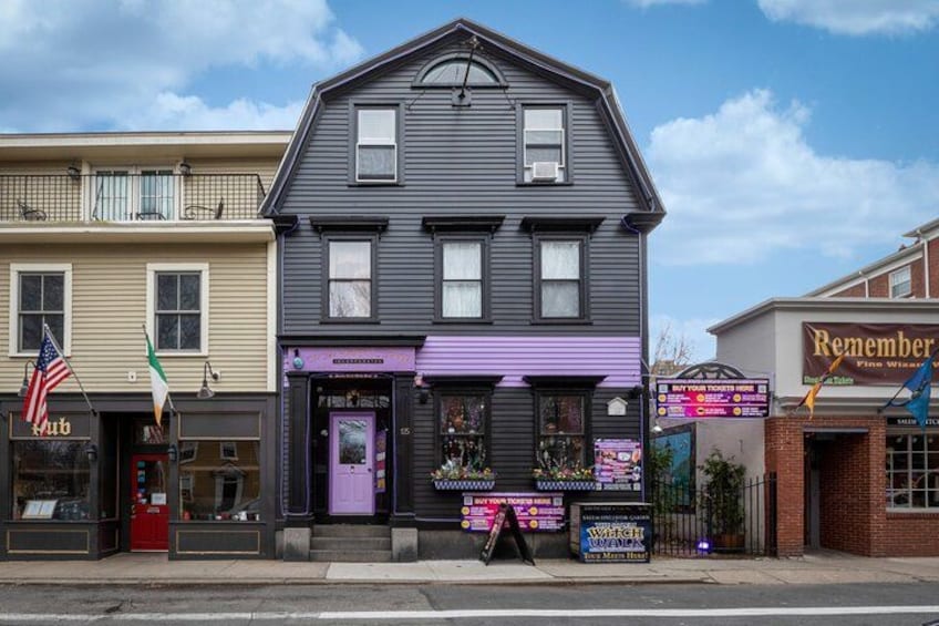 Un bâtiment avec un auvent violet, une devanture de magasin ornée d’une enseigne lumineuse et un drapeau. 2