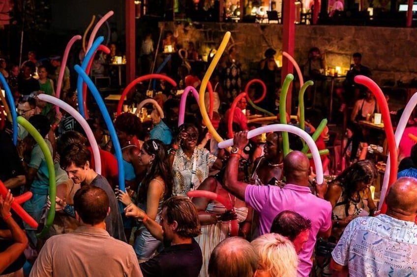A crowded indoor event with people holding colorful balloons. 3