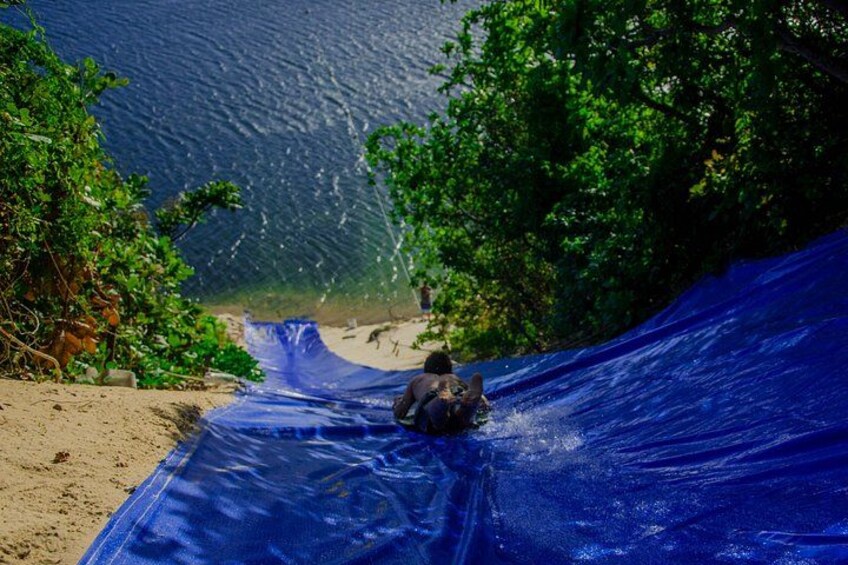 A person sliding down a blue slide at a beach. 3