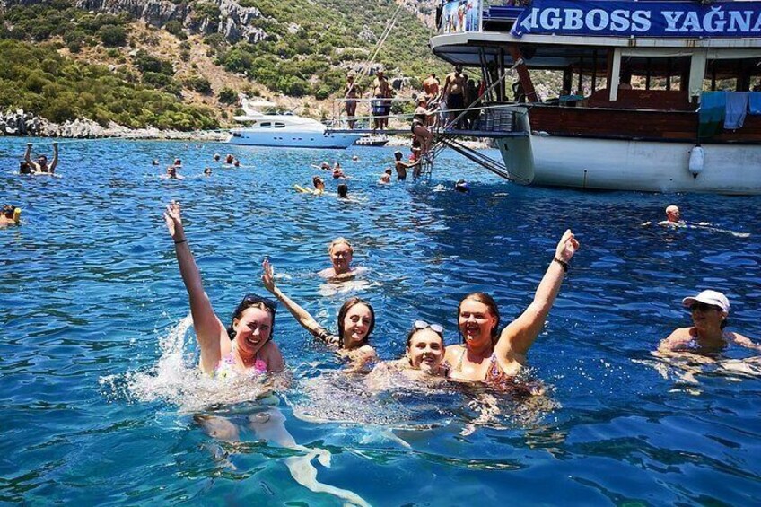 A group of people swimming in a body of water with a boat in the background. 2