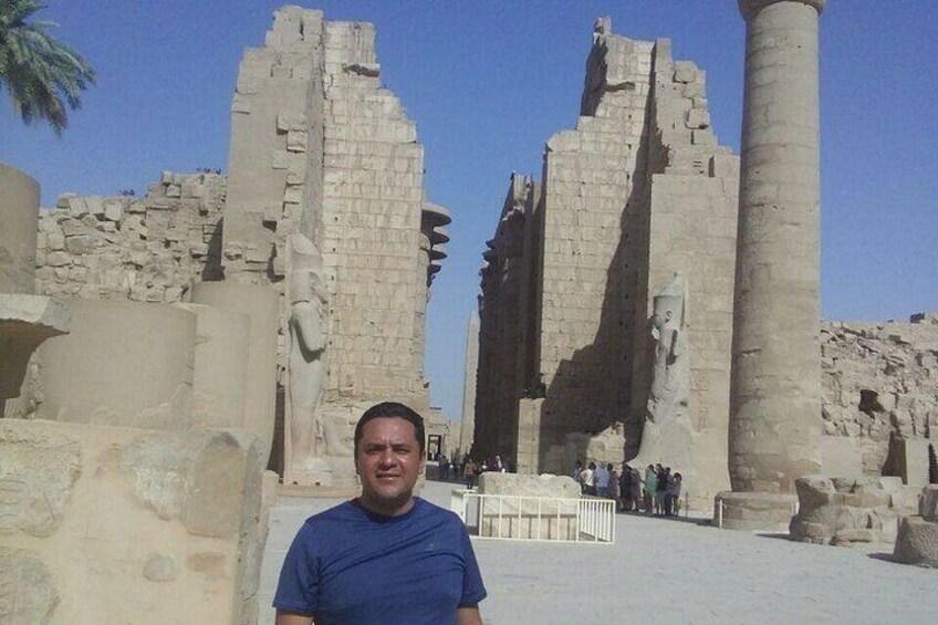 Ancient Egyptian ruins with large stone columns and a pyramid in the background. 5