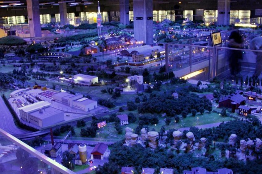 A detailed scale model of a cityscape with various buildings, roads, and greenery. 2